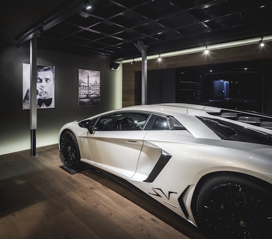 Lamborghini in het wit met zwarte velgen in zijn eigen man cave kelder te bedienen met een lift naar boven en beneden